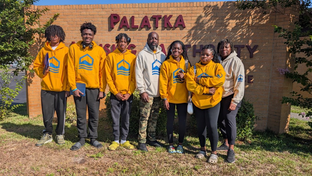 Palatka Housing Authority staff and residents standing together outdoors near a Palatka sign