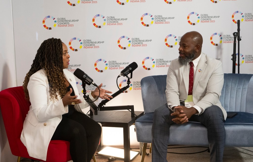 Two people seated and speaking during a recorded conversation