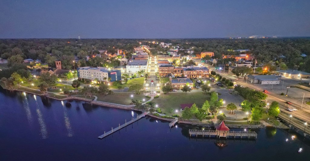 Aerial view of a waterfront city area at dusk with buildings and streetlights