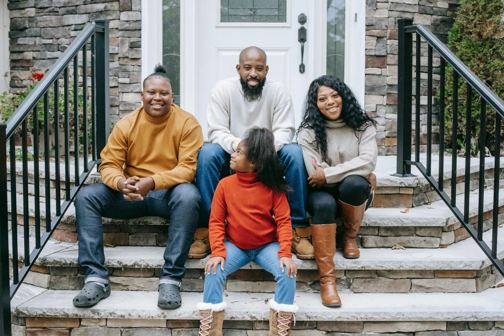 Family seated on the front steps of a residential home